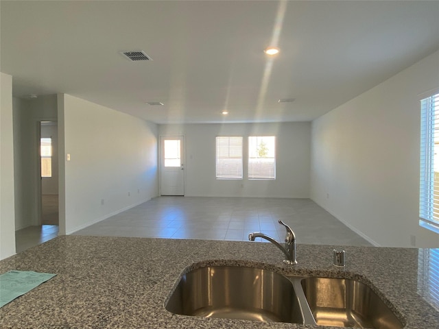 kitchen featuring dark stone countertops, visible vents, a sink, tile patterned floors, and open floor plan