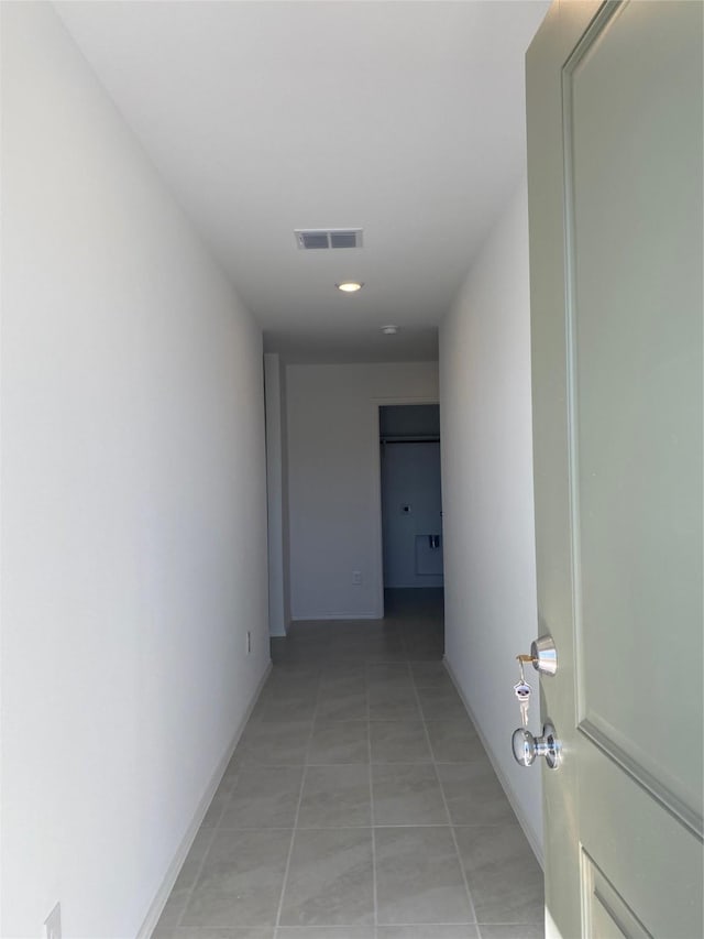 hall with light tile patterned floors, visible vents, and baseboards