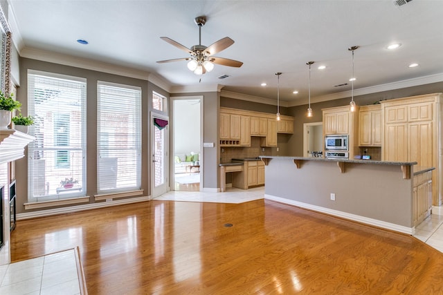 kitchen with tasteful backsplash, crown molding, ceiling fan, a breakfast bar, and appliances with stainless steel finishes