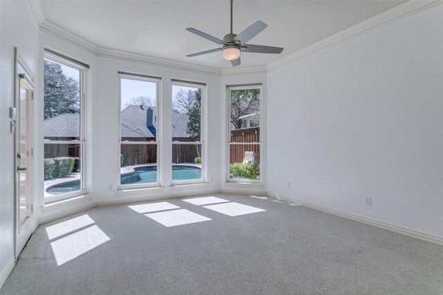 unfurnished room featuring plenty of natural light, carpet, baseboards, and ornamental molding