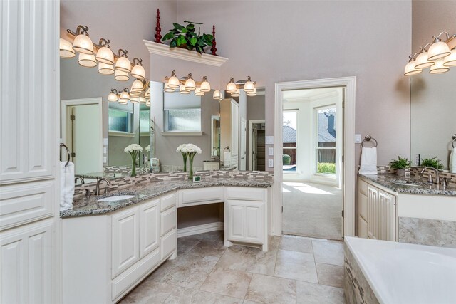 bathroom featuring a bathing tub, two vanities, and a sink