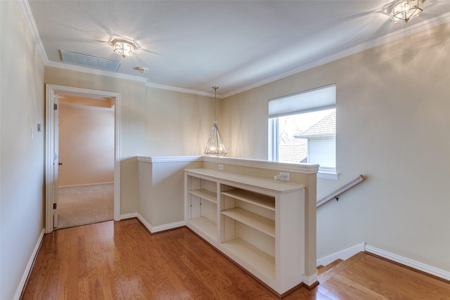 interior space featuring visible vents, ornamental molding, baseboards, and wood finished floors