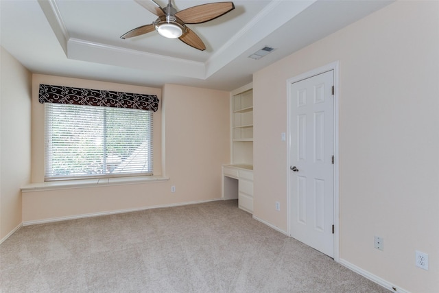 unfurnished bedroom featuring a tray ceiling, visible vents, crown molding, and built in study area