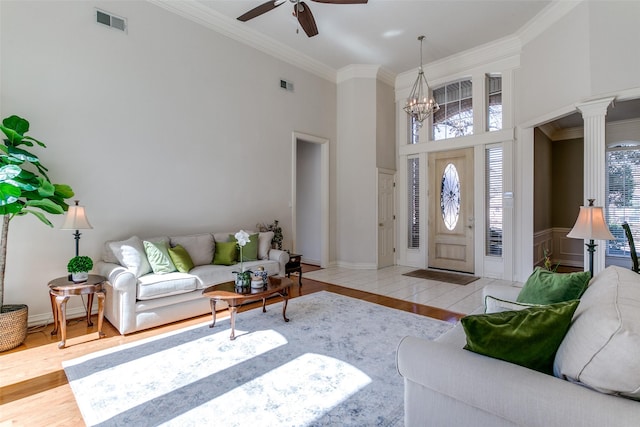 living area featuring wood finished floors, visible vents, ornate columns, and ornamental molding