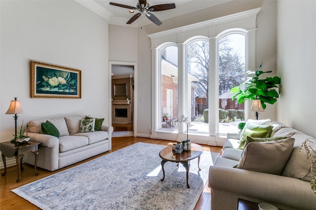 living area with ceiling fan, wood finished floors, and crown molding