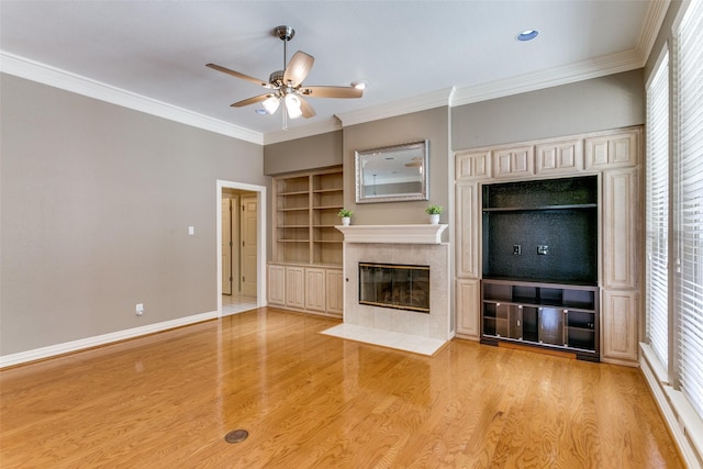 unfurnished living room with a tile fireplace, crown molding, light wood-type flooring, and baseboards