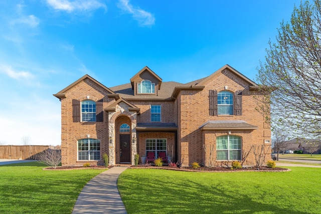 traditional-style home featuring brick siding, a front lawn, and fence