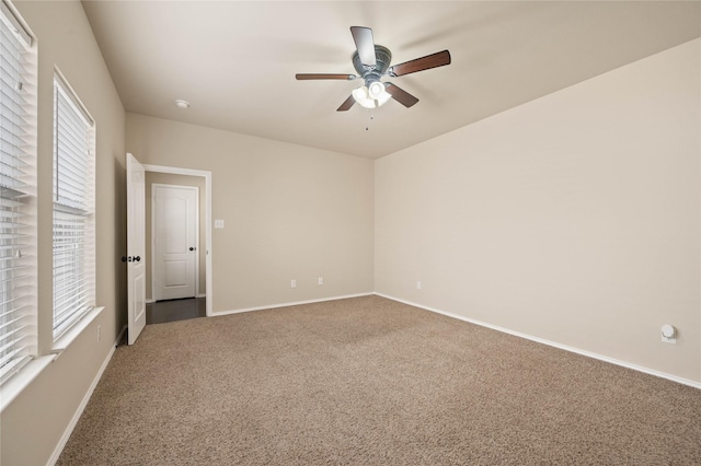 carpeted empty room featuring ceiling fan and baseboards