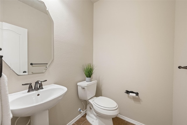 bathroom featuring a sink, baseboards, toilet, and tile patterned flooring