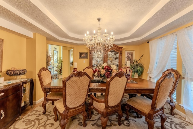 dining room featuring a tray ceiling, a healthy amount of sunlight, and a chandelier