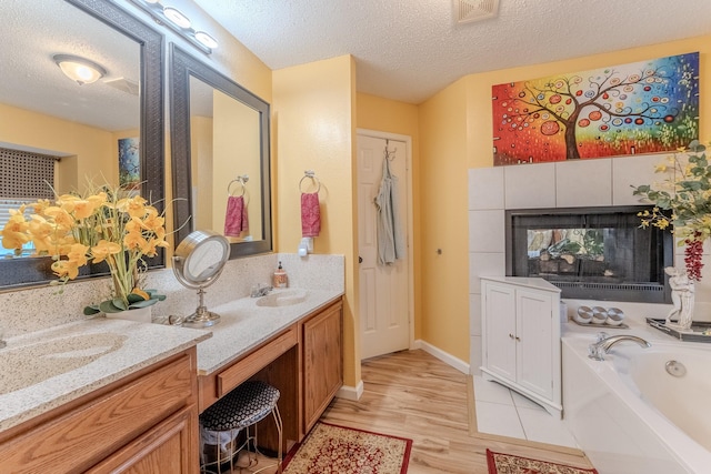 full bath with wood finished floors, a fireplace, visible vents, and a textured ceiling