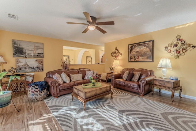 living room featuring visible vents, baseboards, a ceiling fan, and wood finished floors