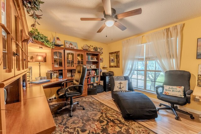 office space with baseboards, a textured ceiling, wood finished floors, and a ceiling fan