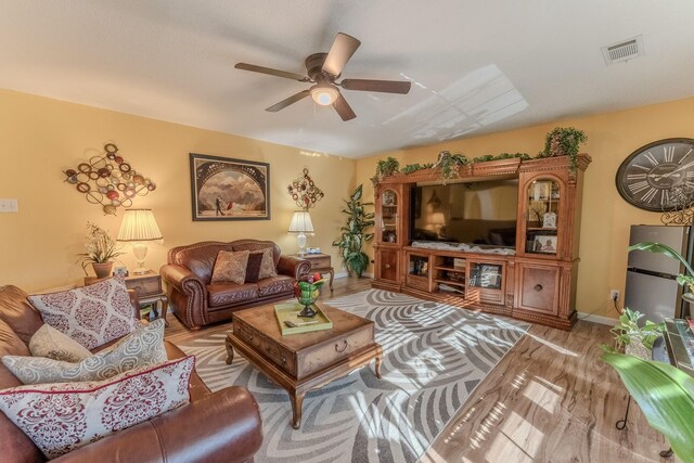 living room featuring visible vents, baseboards, a ceiling fan, and wood finished floors