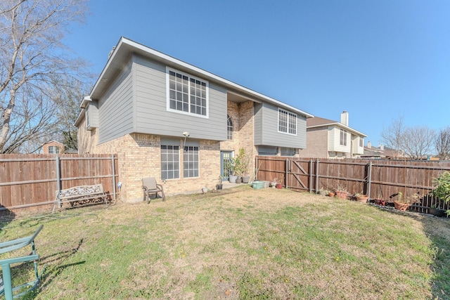 rear view of property with brick siding, a lawn, and a fenced backyard