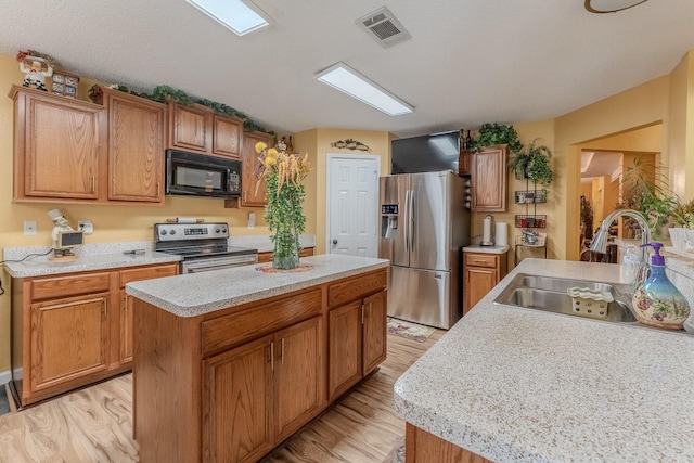 kitchen with visible vents, a kitchen island, a sink, stainless steel appliances, and light countertops