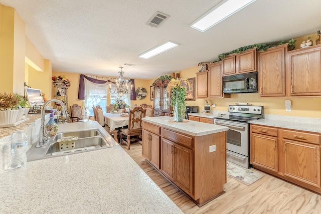 kitchen featuring visible vents, a sink, a kitchen island, black microwave, and stainless steel electric range oven