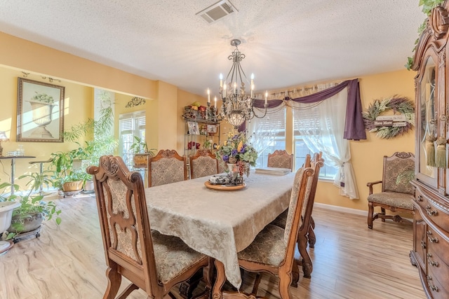 dining room with light wood-style flooring, visible vents, a wealth of natural light, and a chandelier