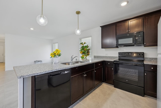 kitchen featuring light stone countertops, dark brown cabinetry, a peninsula, black appliances, and a sink