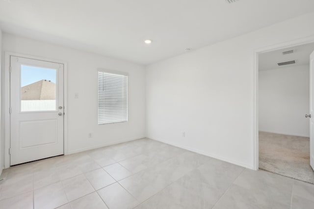 interior space featuring light tile patterned flooring, visible vents, and baseboards