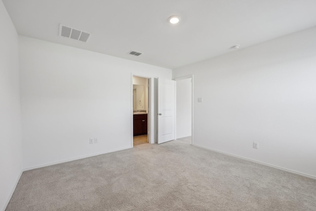 spare room with light colored carpet, visible vents, and baseboards