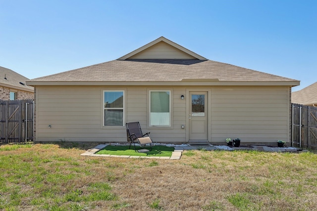 rear view of property with a lawn, a shingled roof, and fence