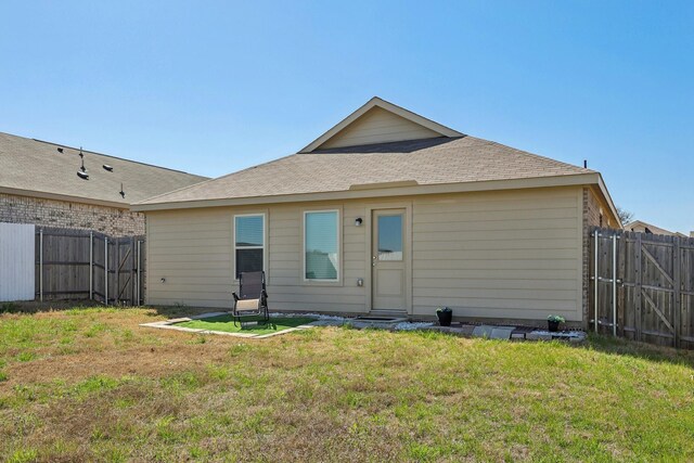 back of house featuring a gate, a lawn, and fence