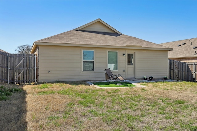 back of house featuring a lawn, fence private yard, roof with shingles, and a gate