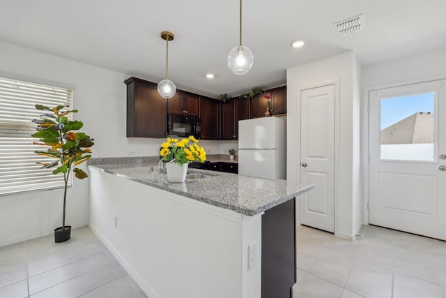 kitchen with dark brown cabinetry, visible vents, freestanding refrigerator, and black microwave