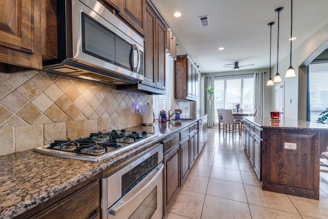 kitchen with visible vents, hanging light fixtures, dark stone countertops, appliances with stainless steel finishes, and light tile patterned flooring