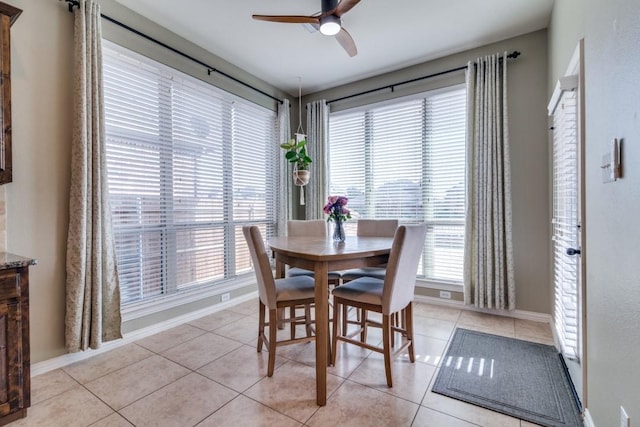 dining space with a ceiling fan, light tile patterned floors, a healthy amount of sunlight, and baseboards