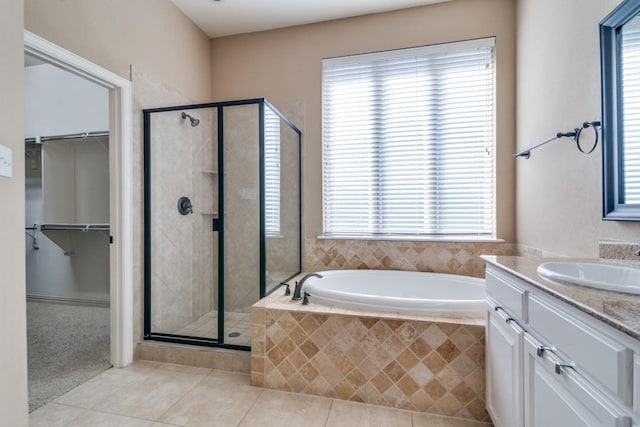 full bathroom featuring tile patterned floors, a shower stall, a bath, and a walk in closet