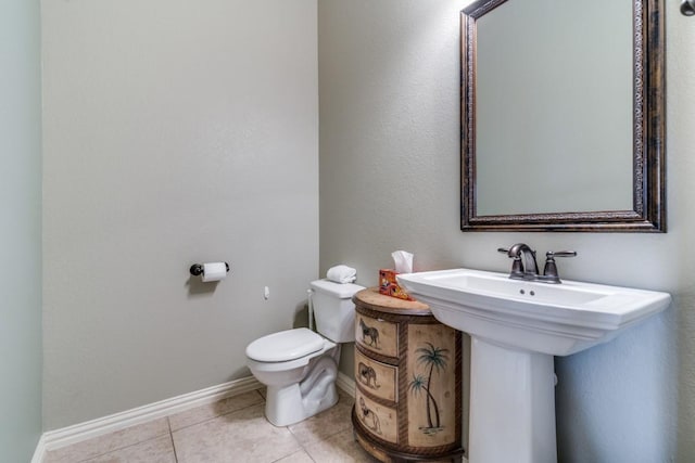 half bath with baseboards, toilet, and tile patterned flooring