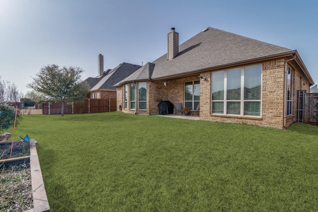 back of property with brick siding, a fenced backyard, a lawn, and a patio area