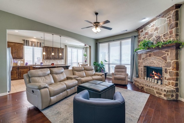 living room with visible vents, ceiling fan, vaulted ceiling, hardwood / wood-style floors, and a fireplace