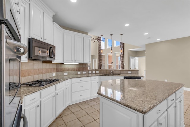 kitchen featuring black appliances, a sink, backsplash, a kitchen island, and light tile patterned flooring