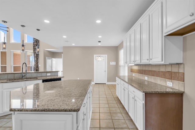 kitchen featuring light tile patterned flooring, backsplash, a kitchen island, and a sink