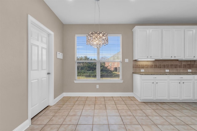 kitchen with baseboards, backsplash, hanging light fixtures, and white cabinetry