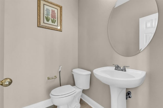 bathroom with baseboards, toilet, and tile patterned flooring