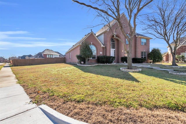 view of front of property featuring a front lawn, fence, and brick siding