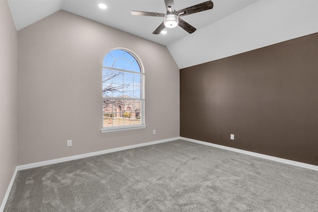 carpeted spare room with vaulted ceiling, baseboards, and ceiling fan