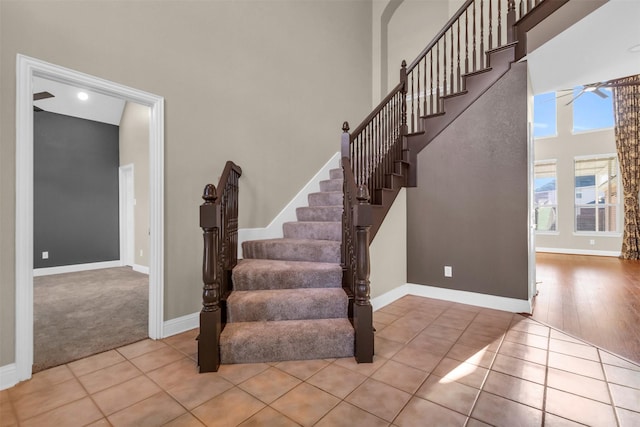 staircase featuring tile patterned floors, baseboards, and a towering ceiling