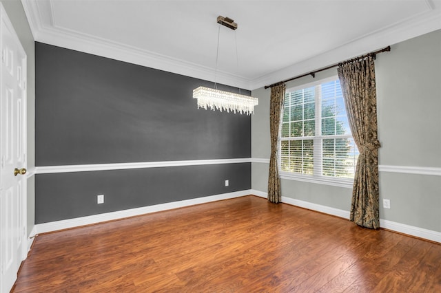 spare room featuring baseboards, wood finished floors, and crown molding