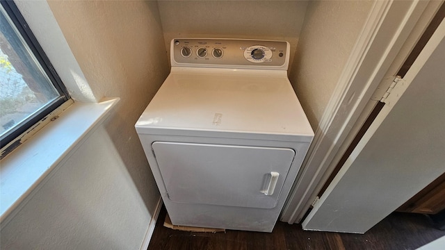 clothes washing area featuring laundry area, washer / clothes dryer, a textured wall, and dark wood-style flooring