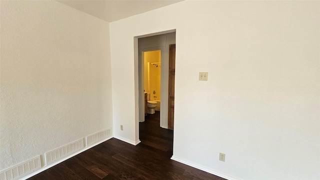 spare room with dark wood finished floors, visible vents, and baseboards