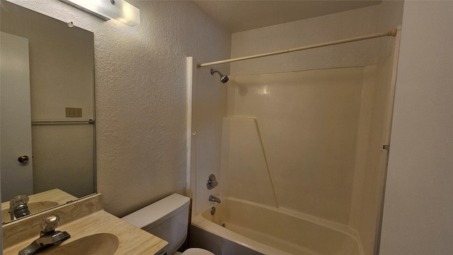 bathroom featuring tub / shower combination, toilet, vanity, and a textured wall