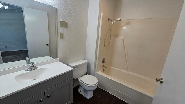 bathroom featuring vanity, wood finished floors, shower / tub combination, toilet, and a textured wall