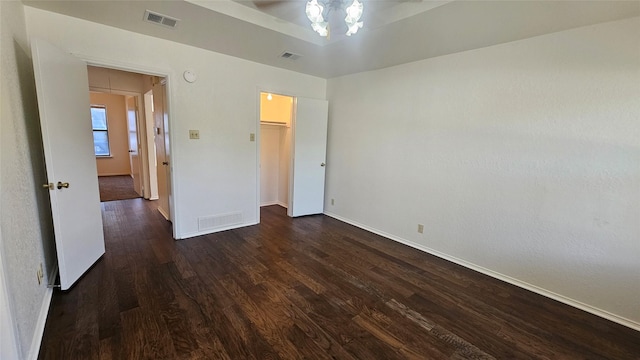 unfurnished bedroom with dark wood-type flooring, attic access, and visible vents