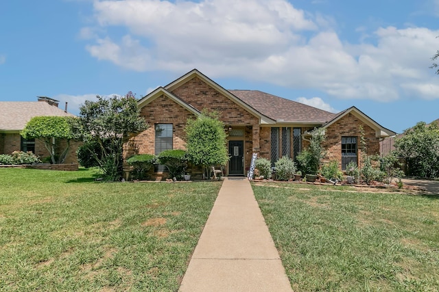 view of front of house with brick siding, a front lawn, and a shingled roof