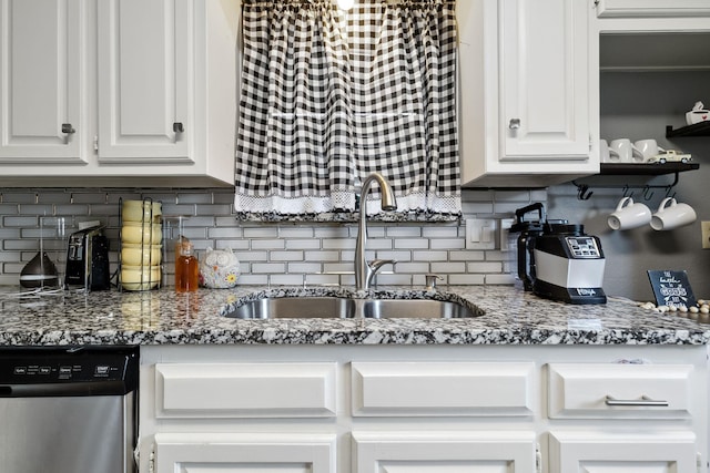 kitchen featuring decorative backsplash, stainless steel dishwasher, stone countertops, white cabinetry, and a sink